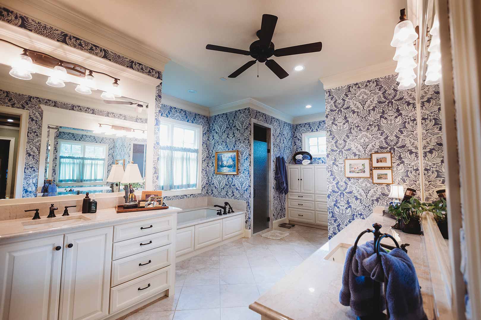 Elegant master bathroom with blue damask wallpaper.