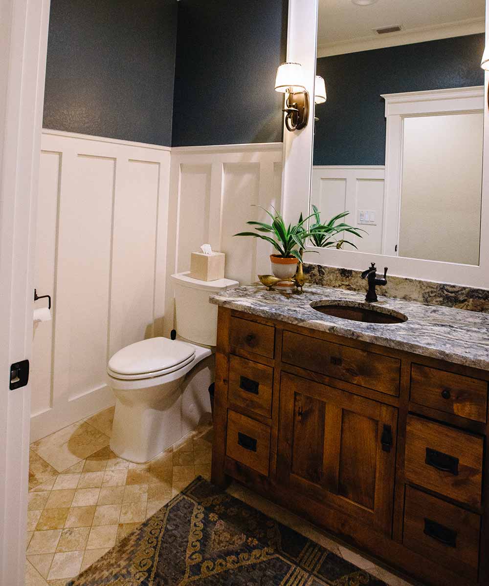 Rustic bathroom with wooden vanity and granite top.