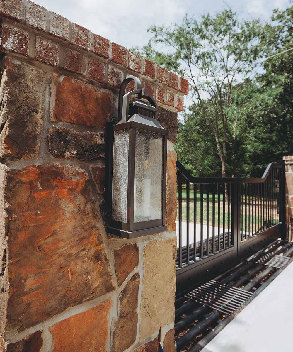 Here's an alt tag for the image: Stone wall lantern near gate.