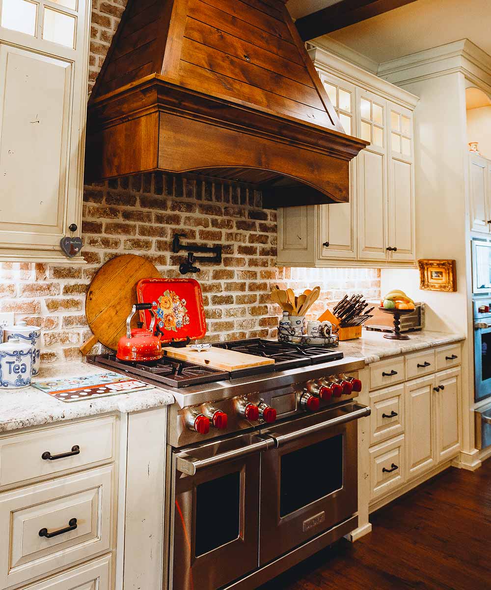 Rustic kitchen with brick backsplash and range.